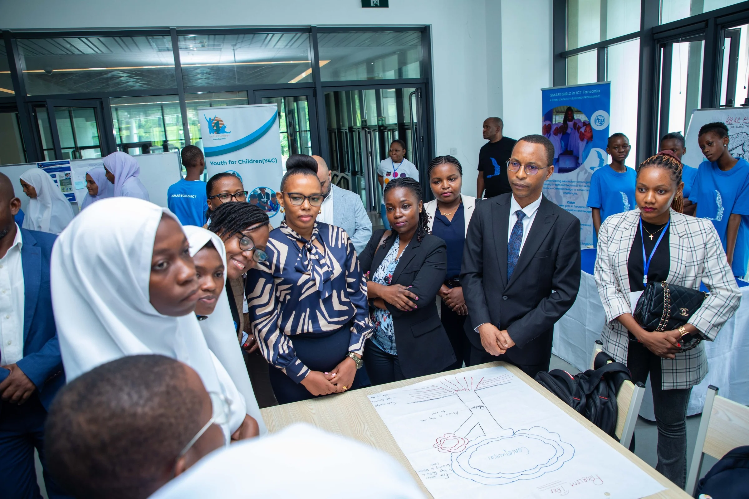 Facilitators and dignitaries reviewing a student HCD poster